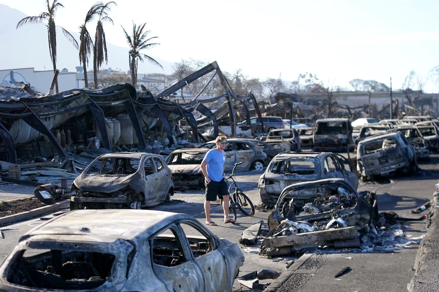 A man walks through wildfire wreckage in Lahaina, Hawaii, in 2023.